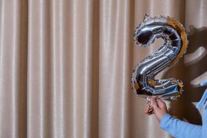 2 dos metálico globo aislado en altas textil antecedentes. saludo tarjeta plata frustrar globo número contento cumpleaños fiesta concepto. Copiar espacio para texto. celebracion fiesta felicidades decoración foto