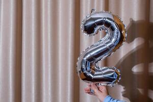 2 dos metálico globo aislado en altas textil antecedentes. saludo tarjeta plata frustrar globo número contento cumpleaños fiesta concepto. Copiar espacio para texto. celebracion fiesta felicidades decoración foto