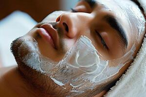 Hispano hombre relajante con blanco facial máscara tratamiento en spa configuración, parte superior ver foto