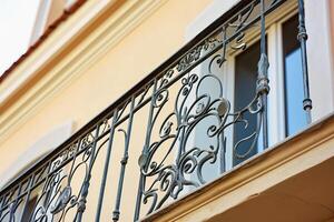 florido forjado hierro balcón barandilla con intrincado diseños en contra beige pared foto