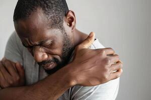 Adult black man experiencing discomfort due to shoulder pain photo