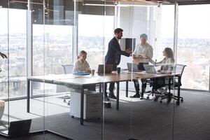 People standing near table, team of young businessmen working and communicating together in office photo