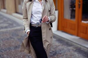 Close up woman in coat with glasses crossing the city street. Blurred background photo