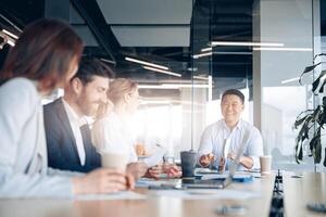 Beautiful business people are using gadgets, talking and smiling during the conference in office photo