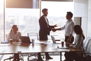 view of confident business partners shaking hands while standing at panoramic window of boardroom photo