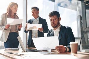 Focused businessmen discussing documents with graphs and charts in a modern office photo