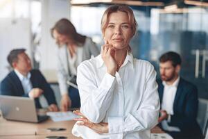 Portrait of beautiful mature confident businesswoman looking strait with her team at background photo