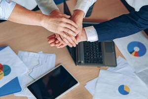 Young business people working at office are holding hands together top view close-up teamwork photo