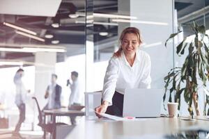 Mature businesswoman working on laptop at modern office.Blurred background photo