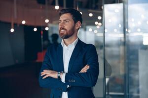 Handsome confident businessman thinking about a job while standing in a modern office photo