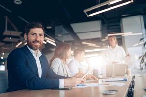 Portrait of creative smiling businessman working on a tablet during a meeting with a team photo