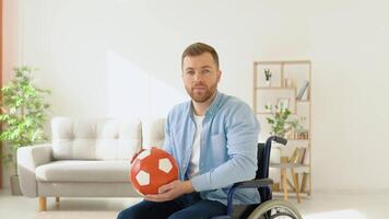 Happy disabled person in a wheelchair with a red ball in his hands before a walk. Concept of inclusion video