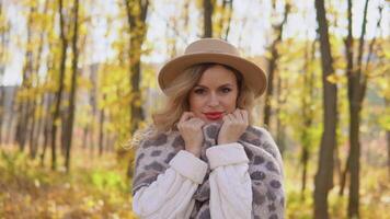 portrait de une souriant content de bonne humeur femme dans une marron chapeau dans l'automne parc. saisonnier les maladies, toux, du froid video