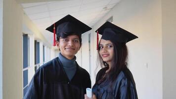 deux Indien diplômés supporter dans le couloir de le Université et Regardez à le caméra. éducation concept video