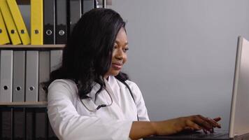 jovem africano mulher médico trabalho com uma computador portátil video