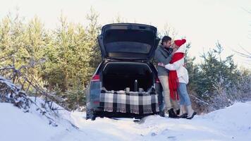 Young couple, a man and a woman hugging and kissing near the car in a winter video