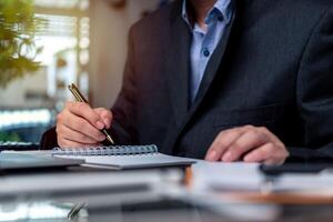 man hands with pen writing on notebook in the office.learning, education and work.writes goals, plans, make to do and wish list on desk. photo