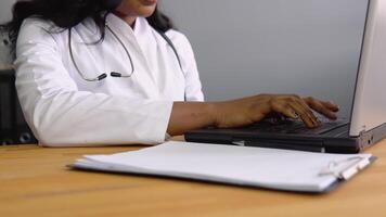 Close up of hands young african woman doctor works with a laptop video