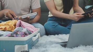 Aziatisch vrouw bereiden naar pak kleren reizen plaatsen met haar vrienden. Aziatisch mooi twee Dames vriend pak dingen in uw reizen zak voor vakantie voor haar vakantie reis video