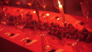 decorated party table with empty wine glasses in red light video