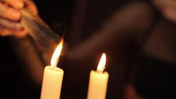 A woman's hand holds a palo santo scent stick over a candle flame video