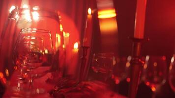 empty wine glasses lined up in a red light on a decorative table. video