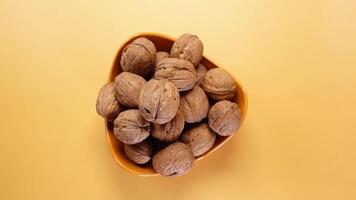 top view of natural walnuts in a bowl on yellow background video