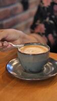 person hand stirring coffee with spoon. video