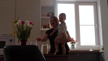 bambino nel La madre di braccia aiuta per fare domestico lavoretti, organizzazione cucina spazio video