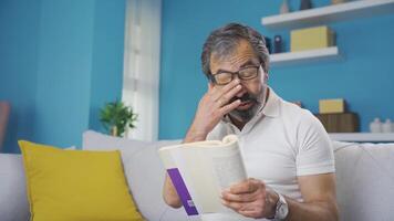 el antiguo hombre tiene un ojo salud problema. él tiene problema leyendo un libro. video