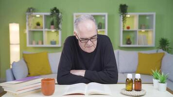 de gammal man är läsning en bok på Hem. video