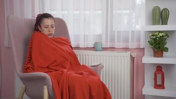 The woman leaning on the heater is cold. video