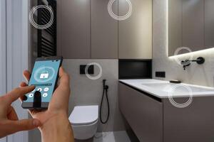 Internet of things. Focus on modern smartphone with blank mockup screen for smart home control system interface in young female customer user hand. Blurred living room interior on background. Close up photo