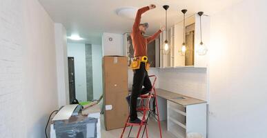 electricista reparando techo ventilador con lamparas adentro. espacio para texto. foto