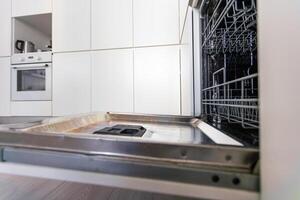 repair of a modern dishwasher with screwdrivers in the kitchen photo