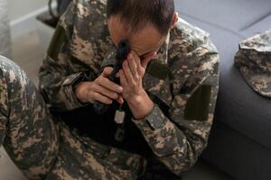 sad soldier has psychological problems holding his head in a squatting position photo