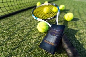 High angle view of mobile phone with tennis equipment on black background photo