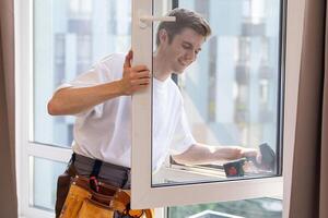 a repairman repairs, adjusts or installs metal-plastic windows in the apartment. glazing of balconies, loggias, verandas in house. production of double-glazed windows to individual sizes photo