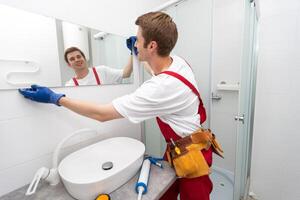 Male repairman hangs the modern electronic bathroom mirror. accessories and furniture for bathrooms and houses photo