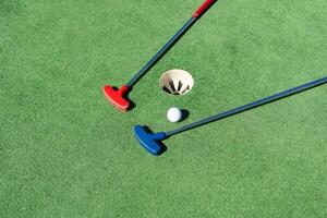 colorful golf putters with golf balls on synthetic grass photo