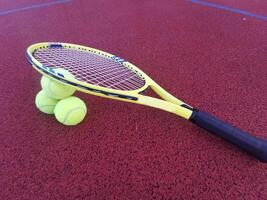 Tennis. Tennis ball and racket on a red background of tennis court with copy space. Sport and healthy lifestyle. The concept of outdoor game sports. photo