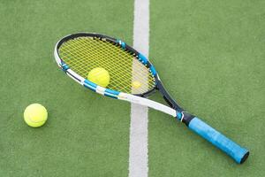 Tennis racket and tennis ball besides the net on outdoor tennis court. photo