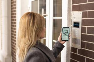 Woman touching smartphone to intercom at office. photo