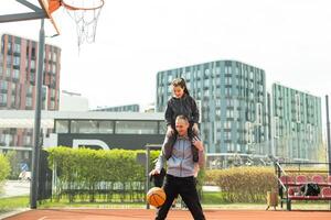Happy father and teen daughter outside at basketball court. photo