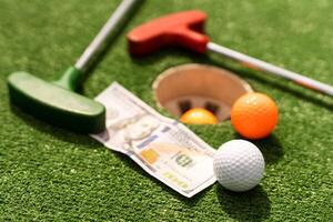 mini golf club, pelota y dinero en el artificial césped foto