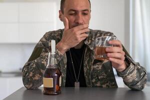 veteran holding bottle of whiskey near face while sitting in wheelchair with closed eyes photo