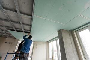 Workers fitting panel into frame of ceiling. photo