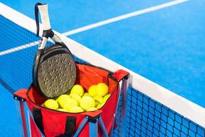 Paddle tennis rackets, balls and basket in court still life photo