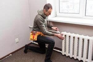 Central heating mechanic and handyman fixing home radiator, gas crisis and seasonal issues. photo