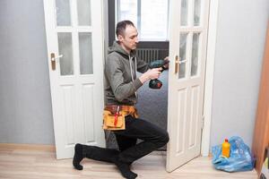 Locksmith, man and maintenance, handyman with home renovation and fixing, change door locks with power tools. Construction, building industry and trade with manual labour, vocation and employee photo